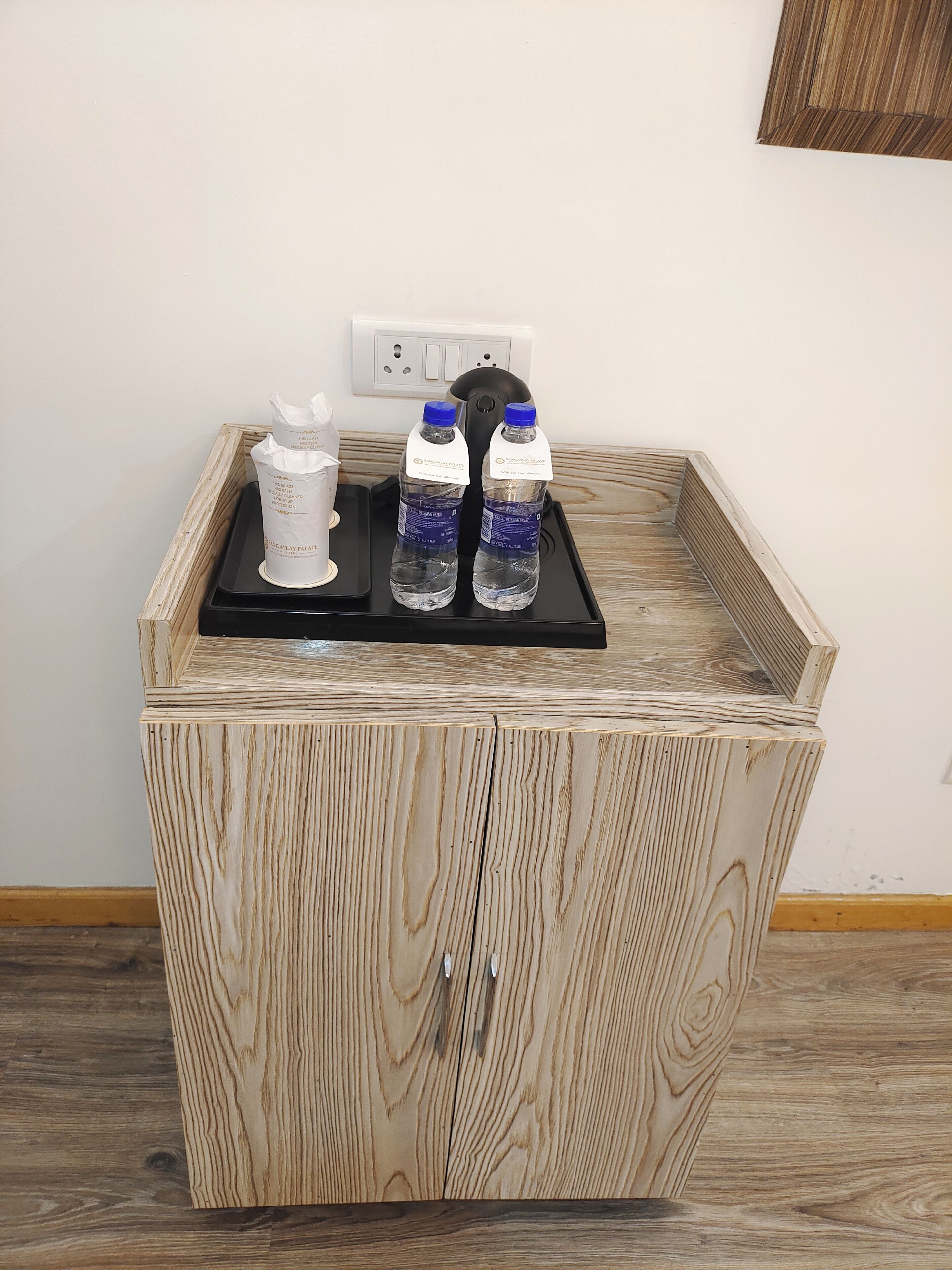 A wooden cabinet with two bottles of water and a white container on top.