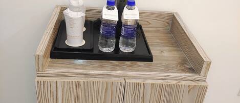 A wooden cabinet with two bottles of water and a white container on top.