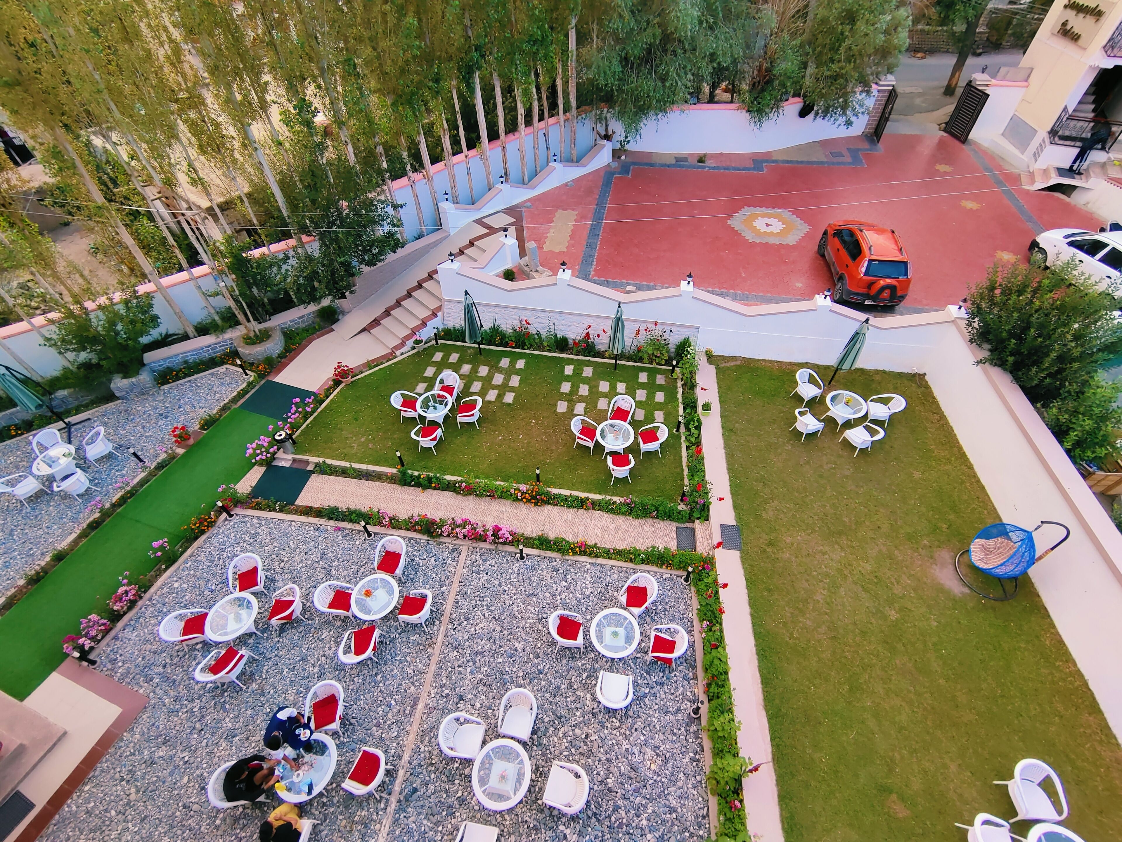 Un patio con zonas de estar al aire libre, una piscina y una zona con tejas rojas.