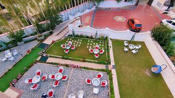 Un patio con zonas de estar al aire libre, una piscina y una zona con tejas rojas.