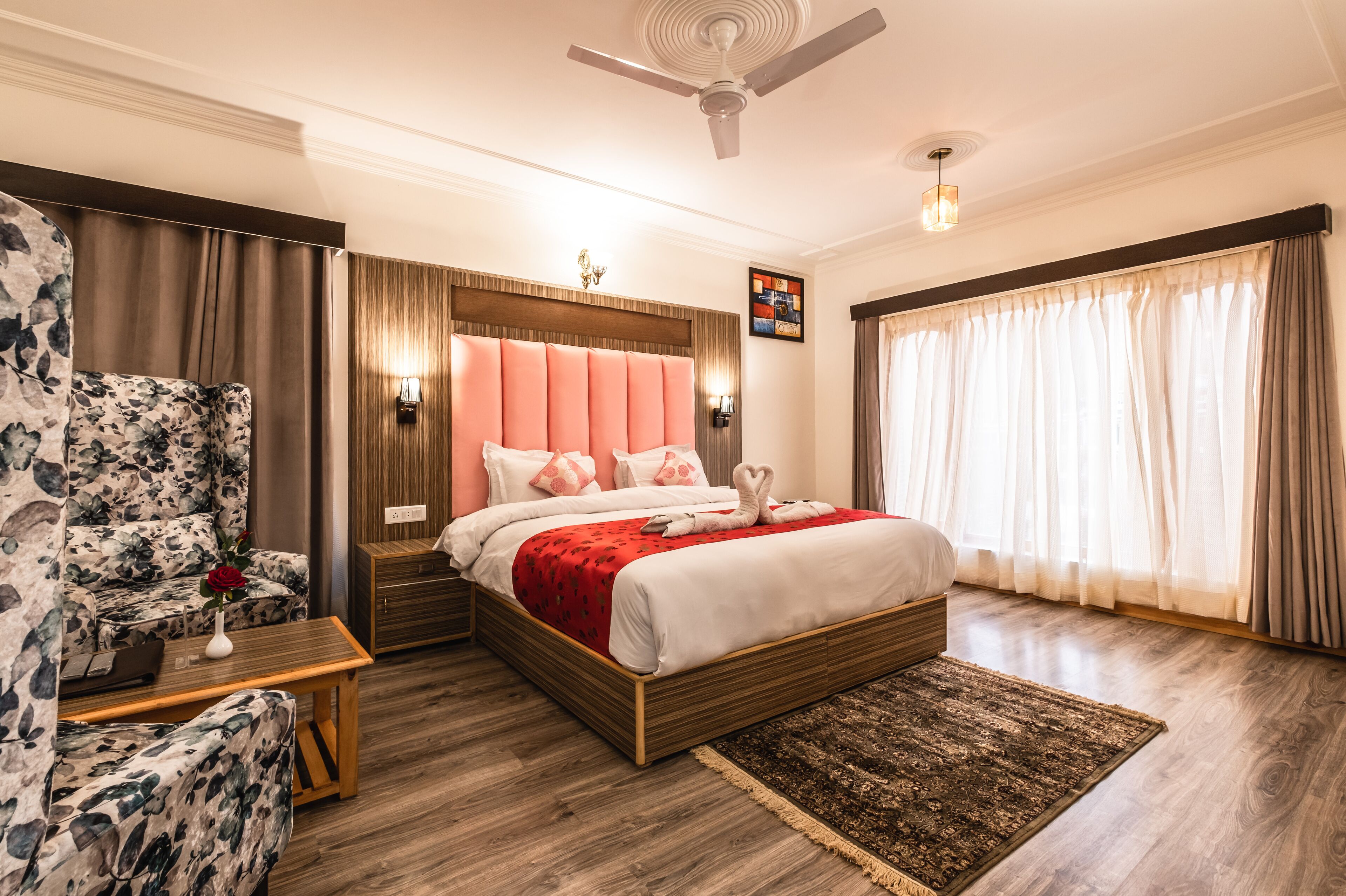A well-lit bedroom with a bed, a nightstand, a floral sofa, and a ceiling fan.