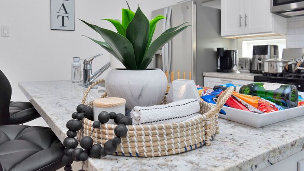 A modern kitchen with white cabinets, a marble countertop, a potted plant, and a tray of snacks. - ✵The Allure✵| Houston Hidden Gem - NRG/Med Center (Houston)