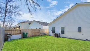 A backyard with a hammock, a green trash bin, and a white building with a garage. - ✵The Allure✵| Houston Hidden Gem - NRG/Med Center (Houston)
