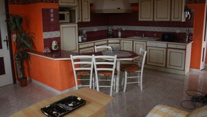 A compact kitchen with a dining area, featuring a microwave, sink, and cabinets. - Seasonal rental of air-conditioned gîtes, swimming pool (Caux)