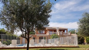 A house with a pool, surrounded by a white fence, and a tree in the foreground. - Seasonal rental of air-conditioned gîtes, swimming pool (Caux)