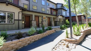 A multi-story residential building with a stone facade, multiple entry doors, and a landscaped front yard with a pathway. - On Golf Course! Lovely Furnished, Private Gas Grill & Laundry. Pool On-site (Mammoth Lakes)