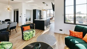 Un salon moderne comprenant un coin repas, une cuisine et une grande fenêtre donnant sur un paysage.