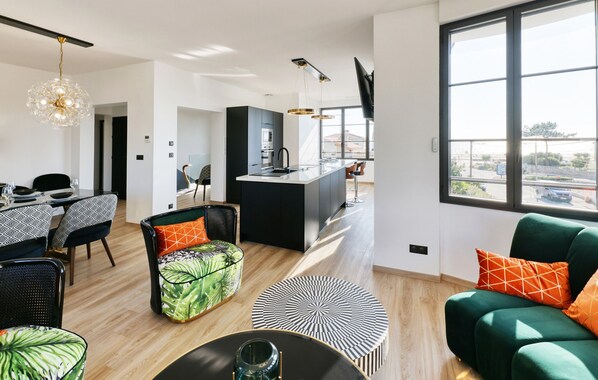 Un salon moderne comprenant un coin repas, une cuisine et une grande fenêtre donnant sur un paysage.