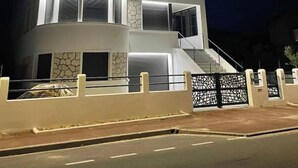 Un immeuble à plusieurs étages, doté d’une façade incurvée, de grandes fenêtres et d’une entrée protégée par un portail.