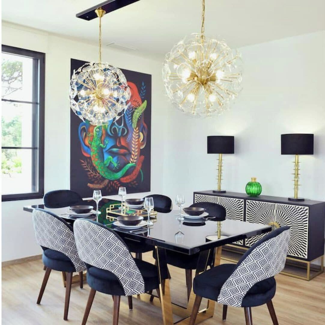 Un comedor con una mesa negra, sillas estampadas y un cuadro abstracto de colores en la pared.