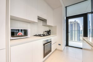 Eine moderne Küche mit weißen Schränken, einer Mikrowelle, einem Herd und einem Backofen.
