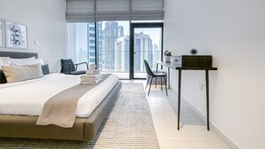 Una moderna camera d'hotel con un grande letto, una scrivania e vista su alti palazzi.