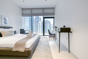 Une chambre d’hôtel moderne, dotée d’un grand lit, d’un bureau et offrant une vue sur de hauts immeubles.