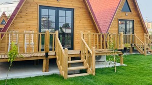Une rangée de petits chalets triangulaires en bois, coiffés de toits rouges, chacun doté d’une grande fenêtre et d’un petit porche.