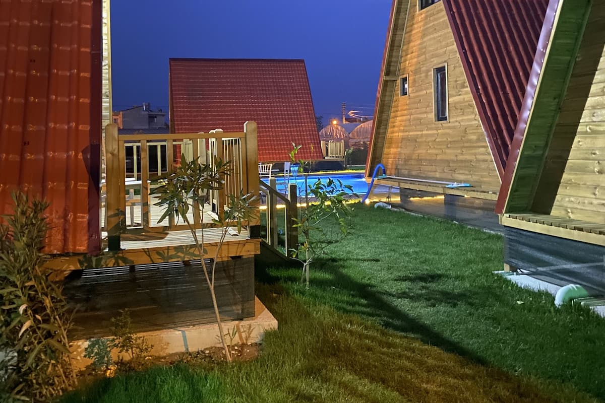 A row of A-frame cabins with a swimming pool in the background.