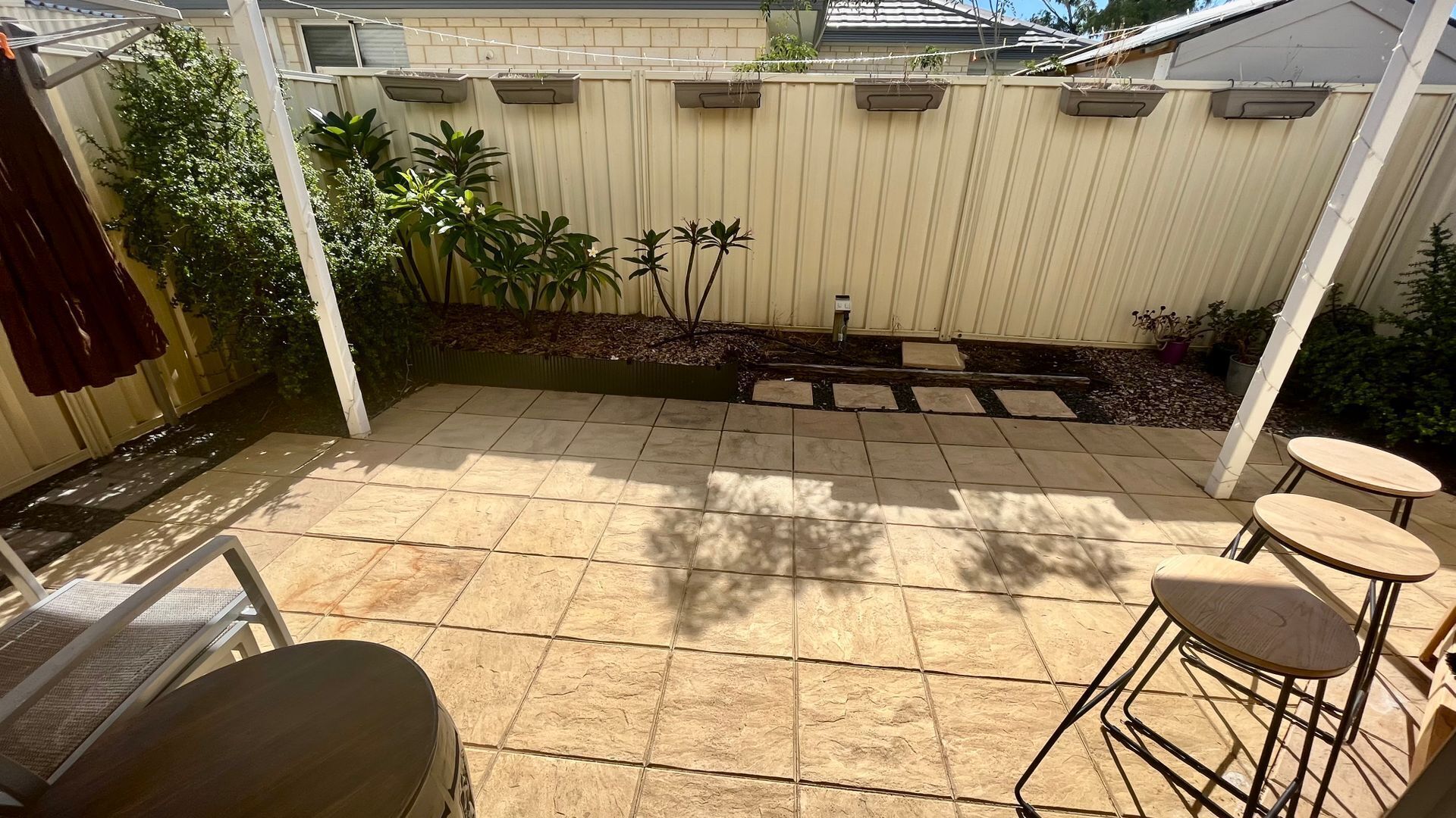 A patio with stone tiles, a white fence, and potted plants.