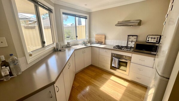 A modern kitchen with white cabinets, a stainless steel stove, a microwave, and a dishwasher.