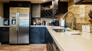 Une cuisine moderne dotée d’appareils électroménagers en acier inoxydable, de meubles de rangement aux couleurs sombres et d’un dosseret carrelé.