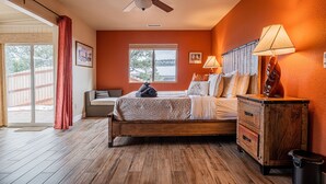 Une chambre avec un lit en bois, un ventilateur de plafond, une table de chevet avec une lampe et une fenêtre donnant sur un beau paysage.