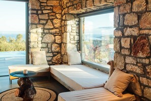 A modern room with stone walls, a large window, a sofa, and a small table.