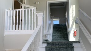 A staircase with white balusters and granite steps leading to an upper floor. - One-of-a-kind! Former Schoolhouse turned mansion for rent! The entire place!! (Port Austin)