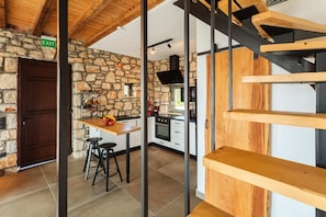 A modern kitchen with stone walls, a wooden table, and bar stools.