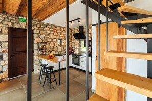 A modern kitchen with stone walls, a wooden table, and bar stools.