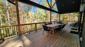 A wooden deck with a table and chairs, overlooking a forested area. - BEAUTIFUL Newly Built Retreat w/Private Marina Boat Slip at Upper Lake Keowee!!! (Sunset)
