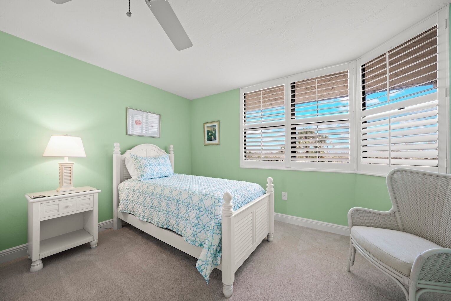 Un dormitorio con cama, mesita de noche, silla y ventana con persianas.