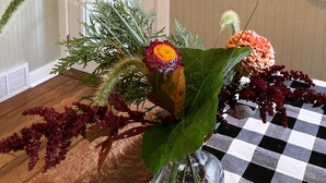 A room with a checkered tablecloth, a door with a window, and a wall-mounted hat rack with hats. - The Cottage at Locavore Farm 32-Acre Prairie, Pond & Farm-to-Table Stay (Grant Park)