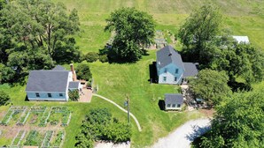 An aerial view of a residential area with two houses, a garden, and a clear sky. - The Cottage at Locavore Farm 32-Acre Prairie, Pond & Farm-to-Table Stay (Grant Park)