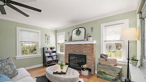 A living room with a fireplace, a sofa, a coffee table, and a bookshelf. - The Cottage at Locavore Farm 32-Acre Prairie, Pond & Farm-to-Table Stay (Grant Park)