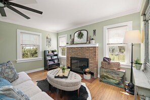 A living room with a fireplace, a sofa, a coffee table, and a bookshelf.