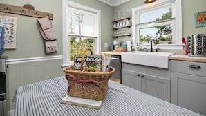 A kitchen with a window, a basket with magazines, and a countertop. - The Cottage at Locavore Farm 32-Acre Prairie, Pond & Farm-to-Table Stay (Grant Park)