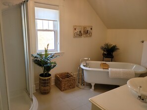 A bathroom with a freestanding bathtub, a window with a view, and a potted plant. - Peaceful House, Calming Gardens + Kitchen + Wi-Fi (Middleton)