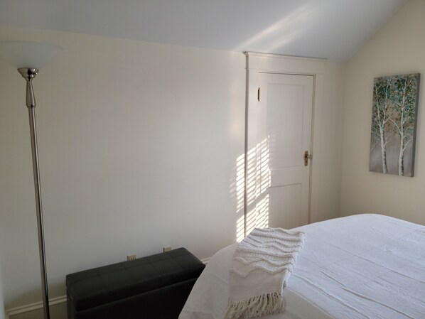 Une chambre à coucher avec un lit, un banc, une porte et un tableau au mur.