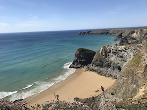 Eine Küstenlandschaft mit Sandstrand, felsigen Klippen und freiem Blick auf den Ozean.