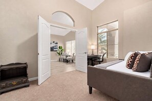 A hotel room with a bed, a desk, a chair, and a view of the outside.