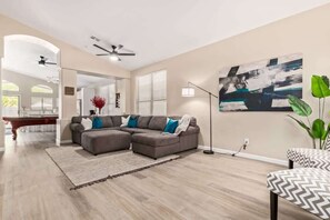 A modern living room with a sectional sofa, a floor lamp, and a large abstract painting. - TPC Scottsdale Retreat|Heated Pool + Putting Green (Scottsdale)