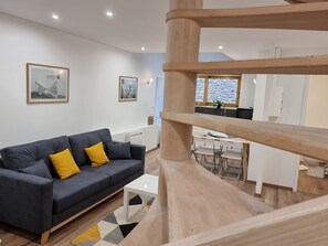 Ein modernes Wohnzimmer mit einem grauen Sofa, gelben Kissen, einem weißen Couchtisch und einem Teppich mit geometrischem Muster.