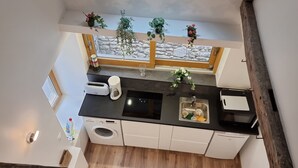 Une cuisine moderne avec un pare-feu en pierre, un four encastré, un évier et une fenêtre donnant sur un paysage enneigé.