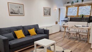 Un salon moderne avec un canapé gris, une petite table blanche et un tapis à motifs géométriques.