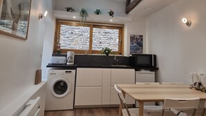 Une cuisine compacte équipée d’un lave-linge, d’une machine à café et d’un coin repas avec une table et des chaises.