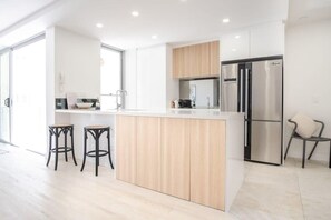 A modern kitchen with a central island, stainless steel appliances, and a view to the outside.
