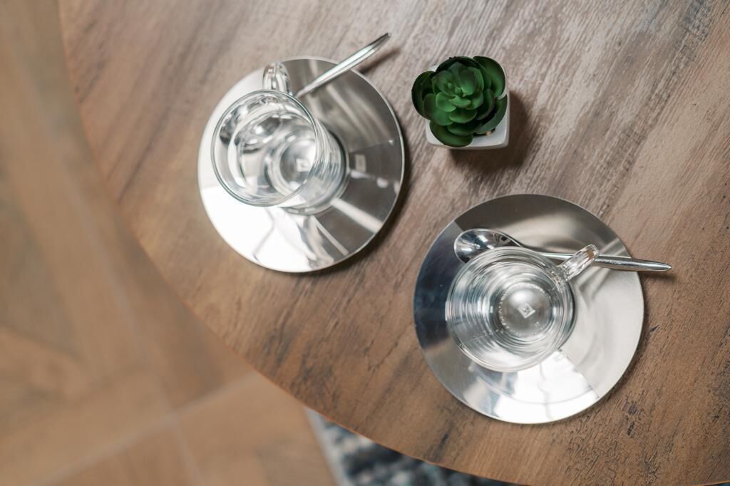 Dos platos de acero inoxidable con una cuchara sobre una mesa de madera.