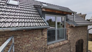 Een gebouw van baksteen met een metalen dak, een raam met een metalen hekwerk en een deur.