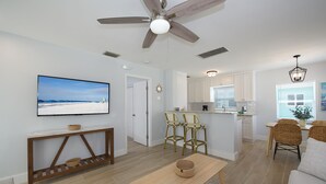 Une cuisine moderne avec des meubles blancs, un îlot central et un coin repas doté de chaises en osier.