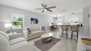 A modern living room with a sofa, coffee table, and a dining area with chairs and a table. - Mid-Island, completely renovated duplex, 1bedroom/1 bath- CLOSE TO THE BEACH! (Fort Myers Beach)