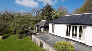 A white building with a black roof, a stone pathway, and a small garden. - Higher Mapstone (Lustleigh)