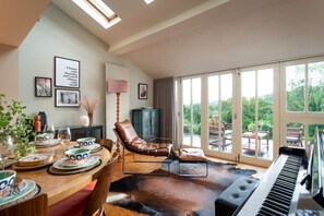 A dining area with a table set for four, a piano, and a leather rug. - Higher Mapstone (Lustleigh)